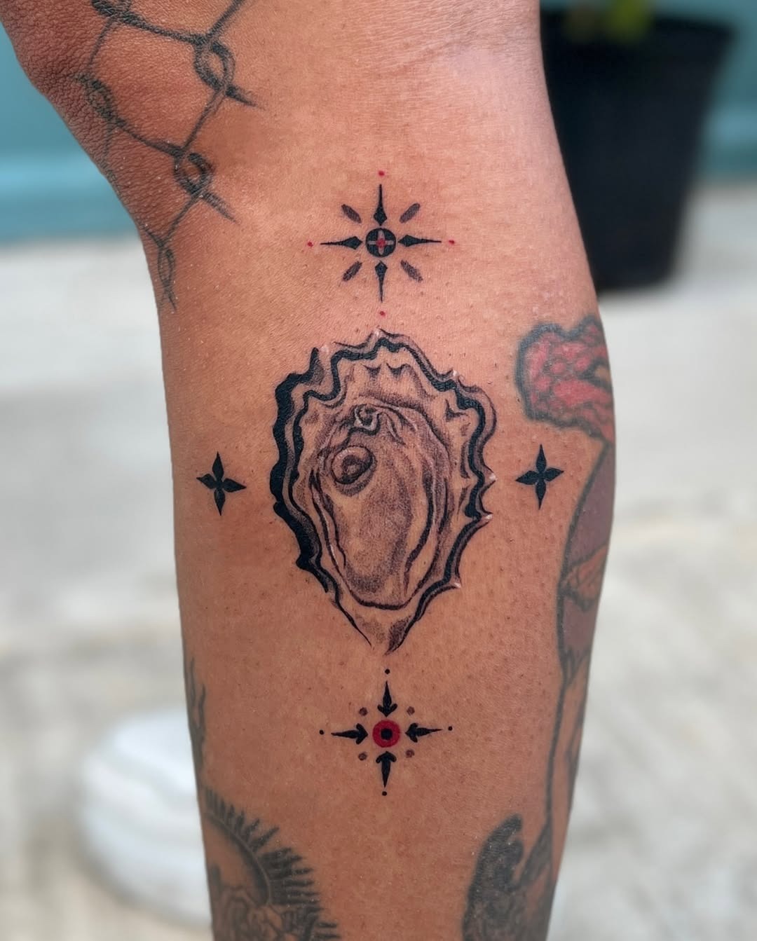This oyster tattoo showcases a beautifully detailed shell with a striking black outline.