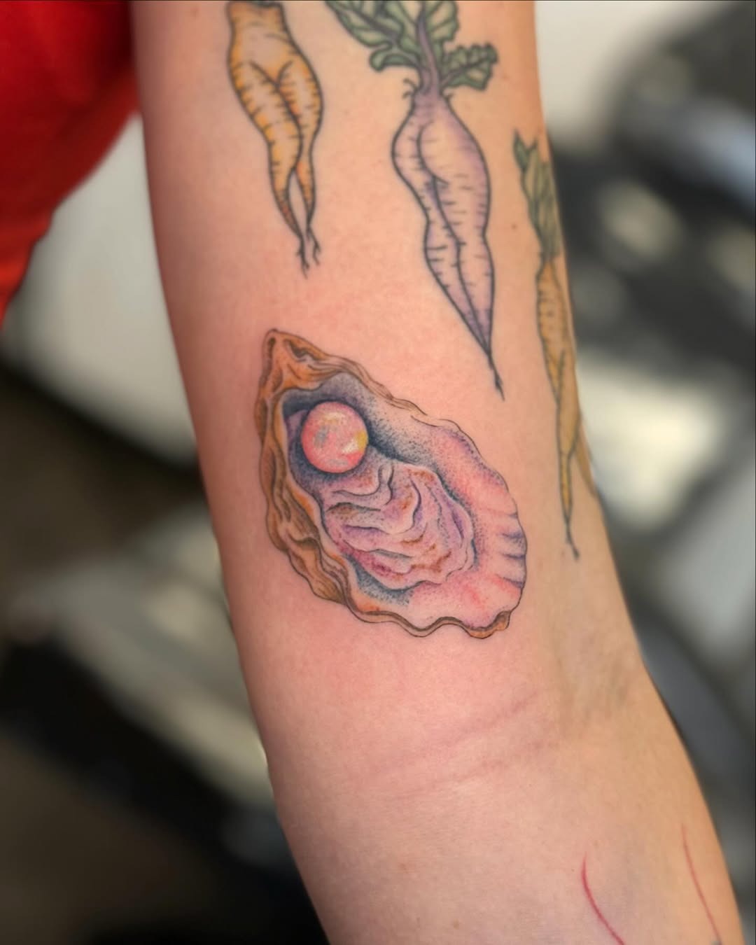 This oyster tattoo showcases a beautifully detailed shell revealing a radiant pearl.