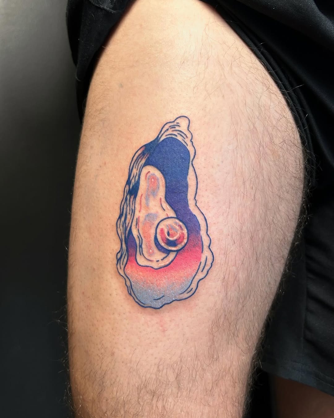 This tattoo features a beautifully colored oyster shell, blending shades of blue and pink.