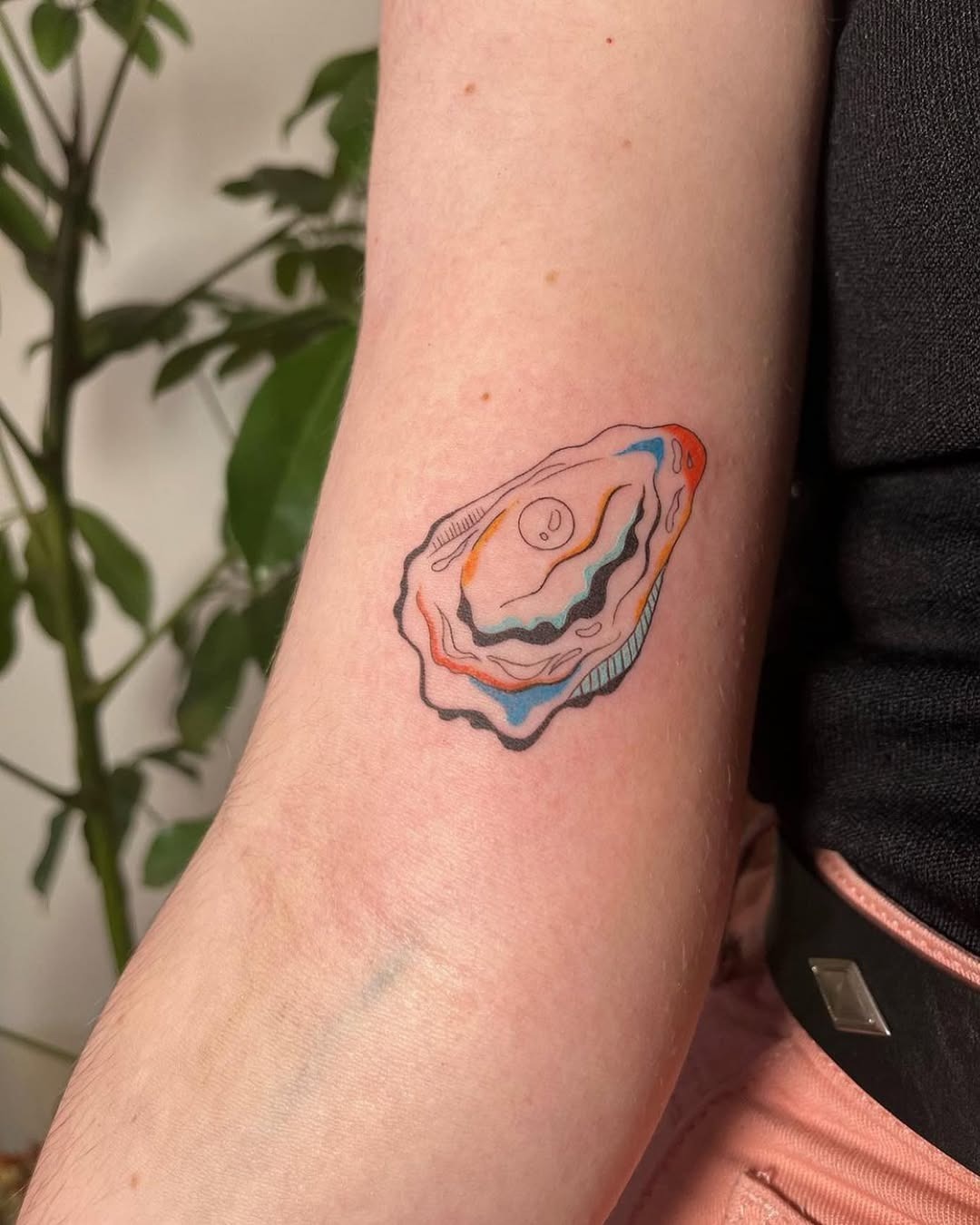 This charming oyster tattoo showcases delicate lines and playful colors, adding a lively touch to the skin.