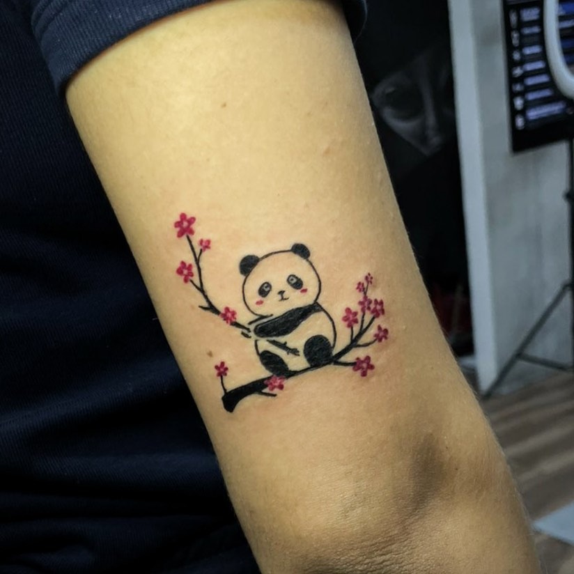 Playful panda perched on cherry blossom branch Tattoo Design