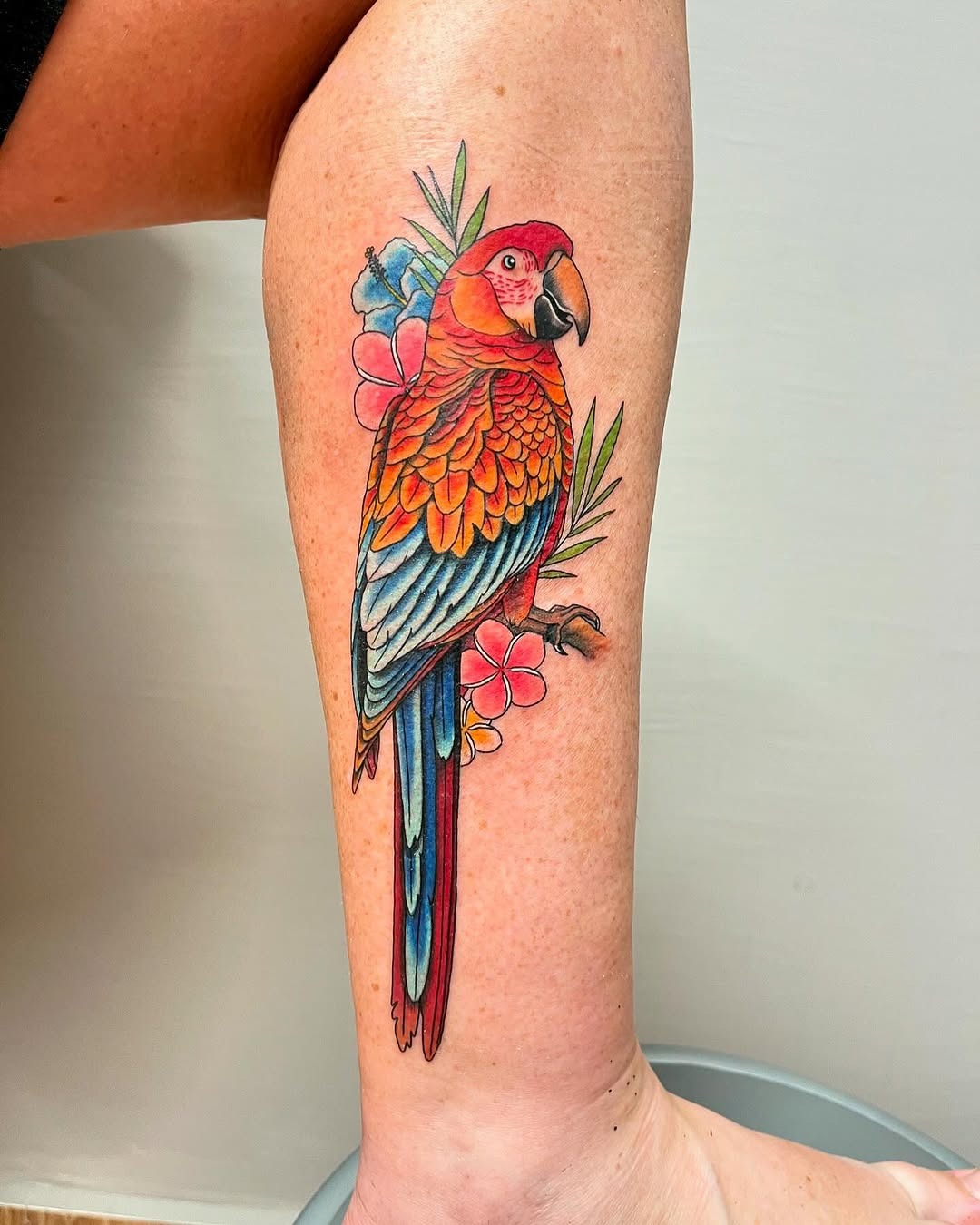 Vibrant parrot tattoo with floral accents Tattoo Design