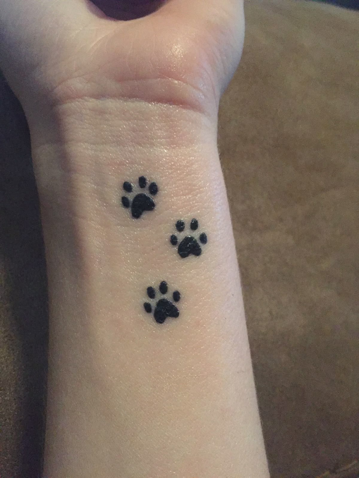 Three Tiny Black Paw Prints Tattoo Design