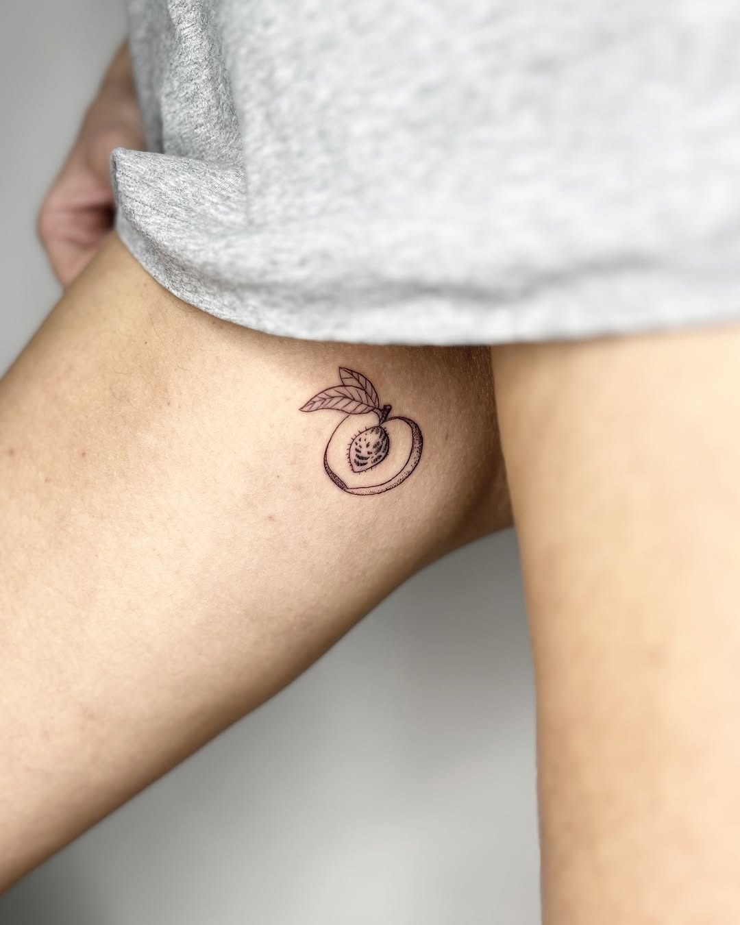 Chic and minimalist peach thigh tattoo design Tattoo Design