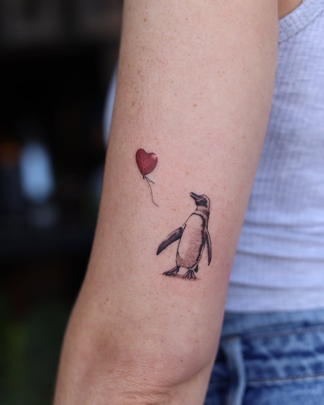 Charming penguin tattoo with a whimsical balloon Tattoo Design