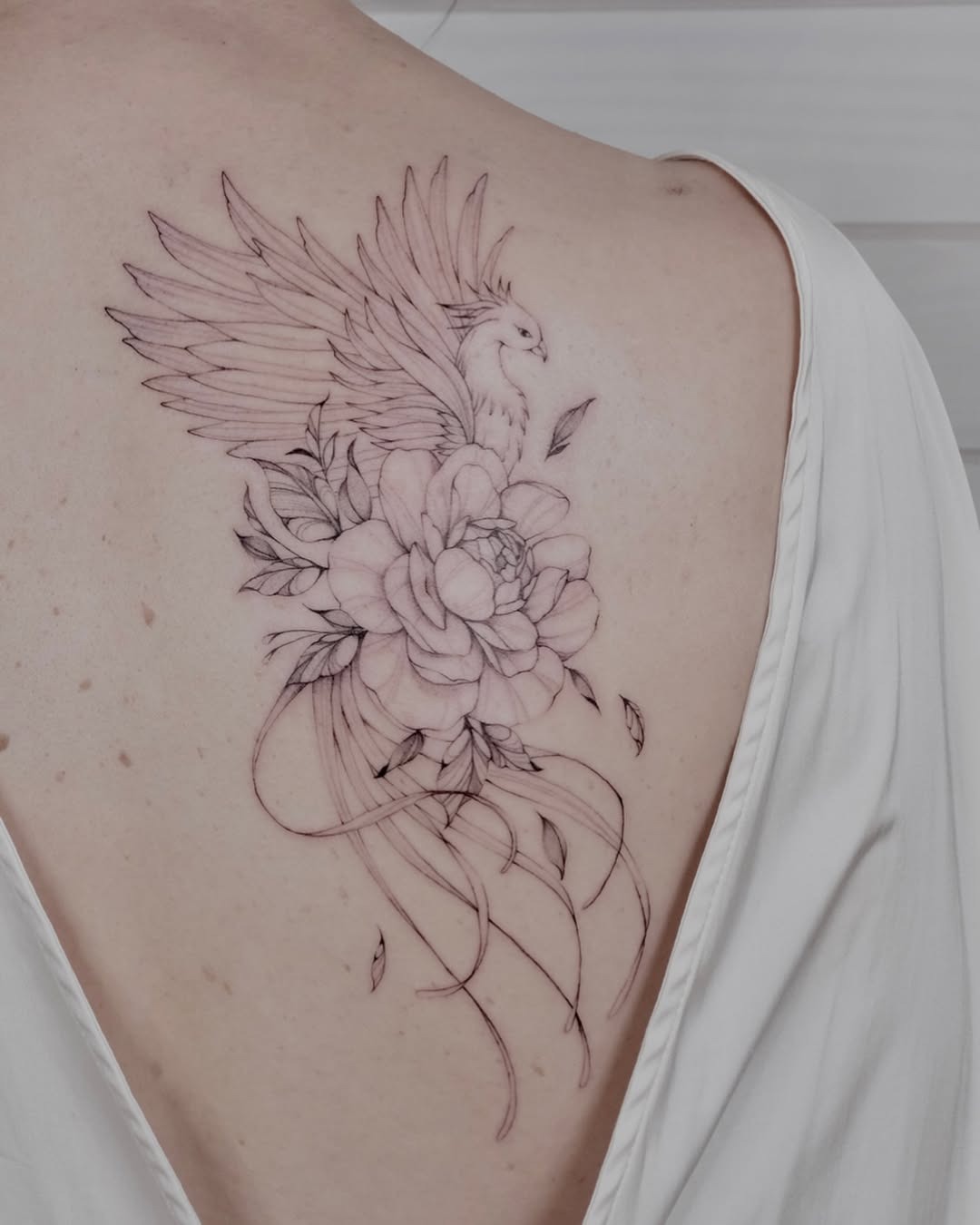 Elegant phoenix tattoo with floral details Tattoo Design