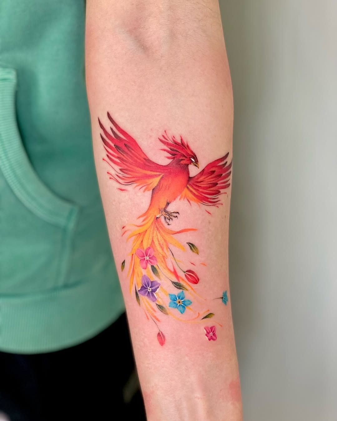 Stunning phoenix tattoo with vibrant floral accents Tattoo Design