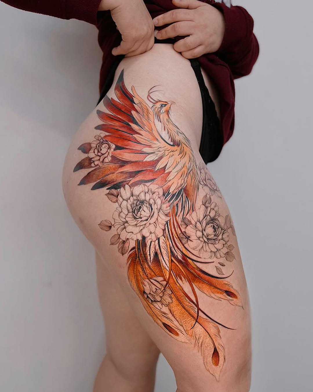 Stunning thigh phoenix tattoo with floral elements Tattoo Design