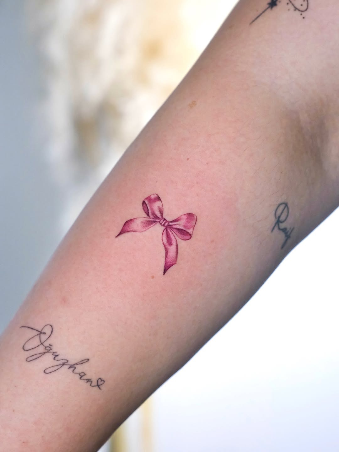 Charming pink bow tattoo on the arm Tattoo Design