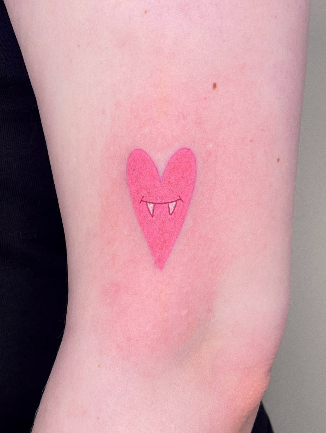 Charming pink heart with playful vampire fangs Tattoo Design