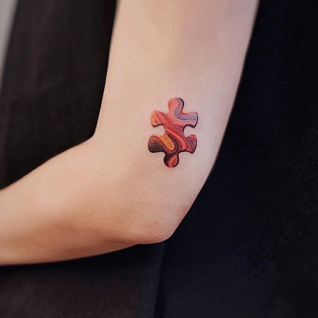 Colorful puzzle piece tattoo on the elbow Tattoo Design