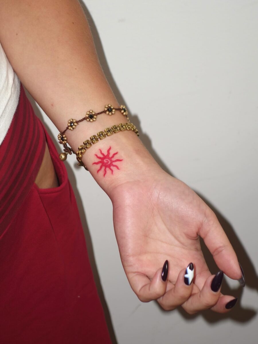 Vibrant red sun tattoo on wrist Tattoo Design