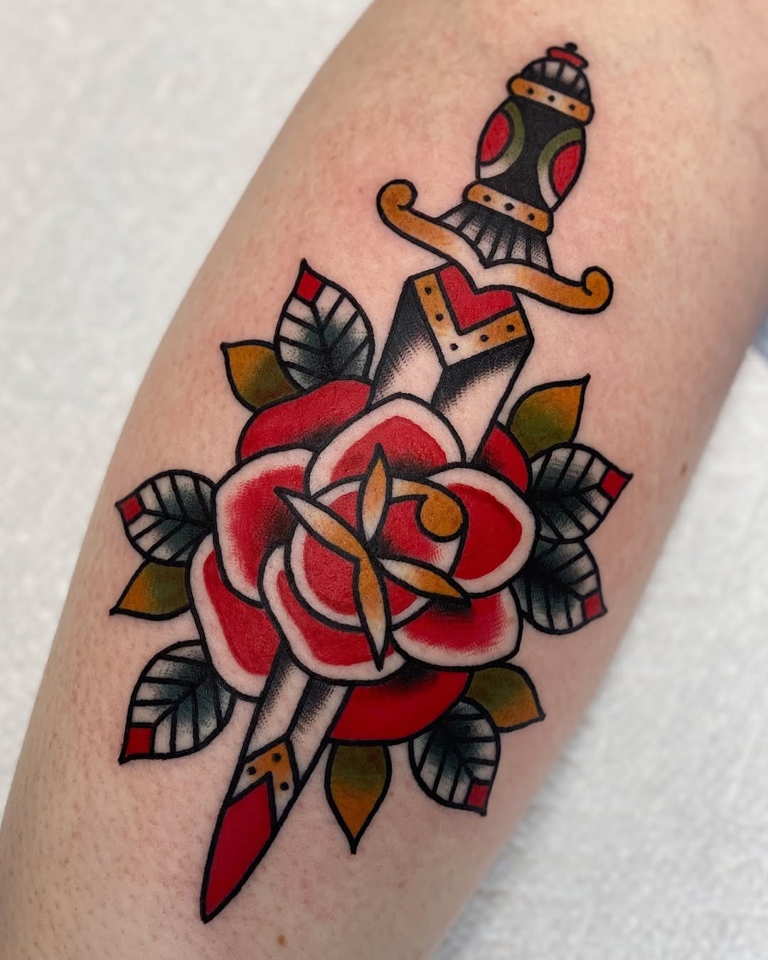 Bold rose tattoo with dagger and leaves Tattoo Design