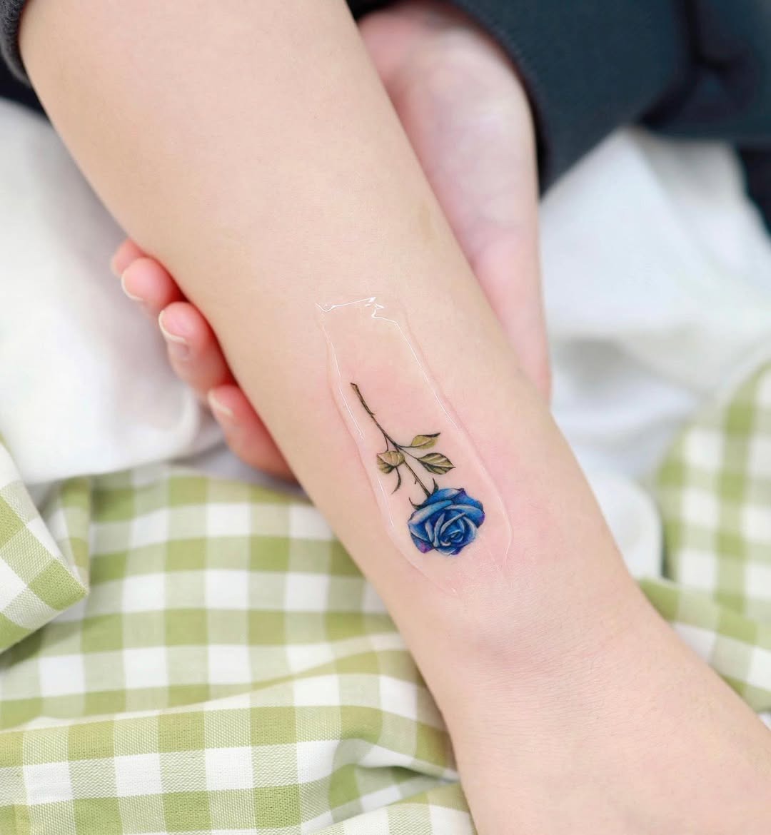 Delicate blue rose tattoo on an arm Tattoo Design