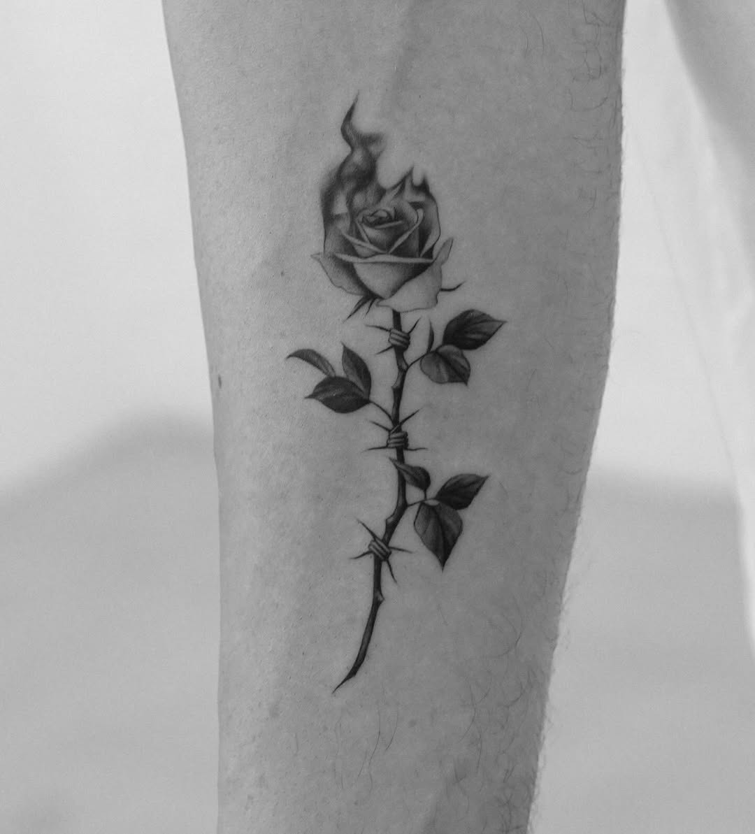 Elegant black rose tattoo with a fiery twist Tattoo Design