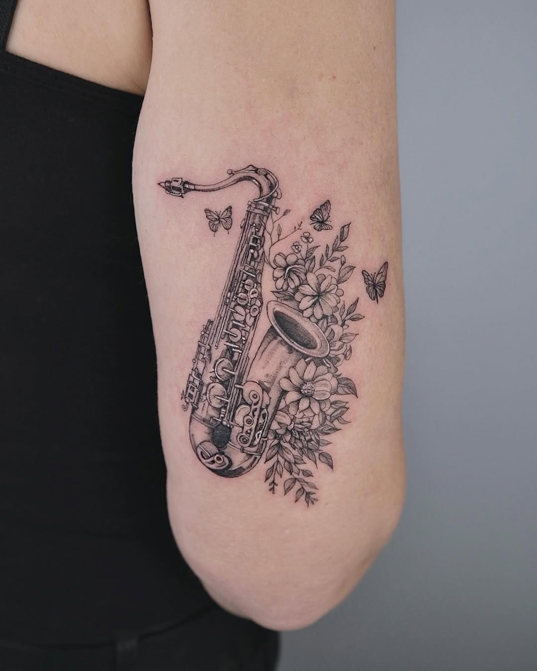 Artistic saxophone tattoo surrounded by flowers Tattoo Design