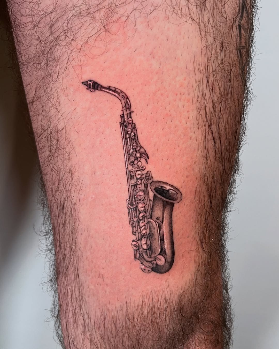 Intricate saxophone tattoo on the leg Tattoo Design