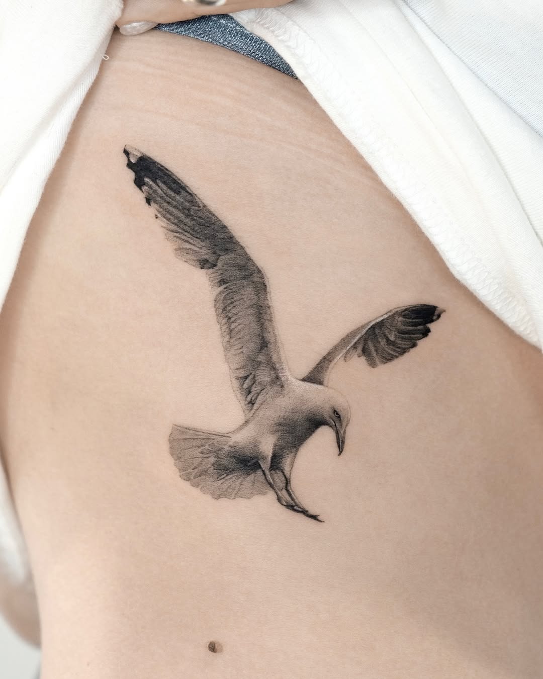Realistic seagull tattoo in flight on skin Tattoo Design