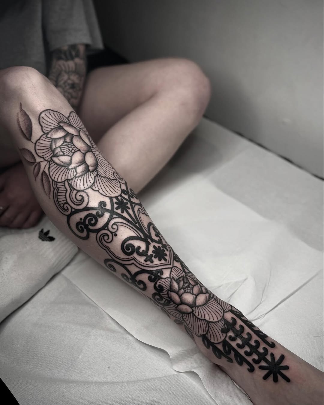 Elegant floral shin tattoo design in black ink Tattoo Design