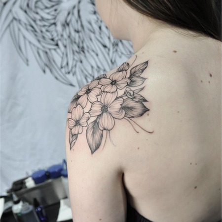 This shoulder cap tattoo is a delicate and artistic representation of cherry blossoms.
