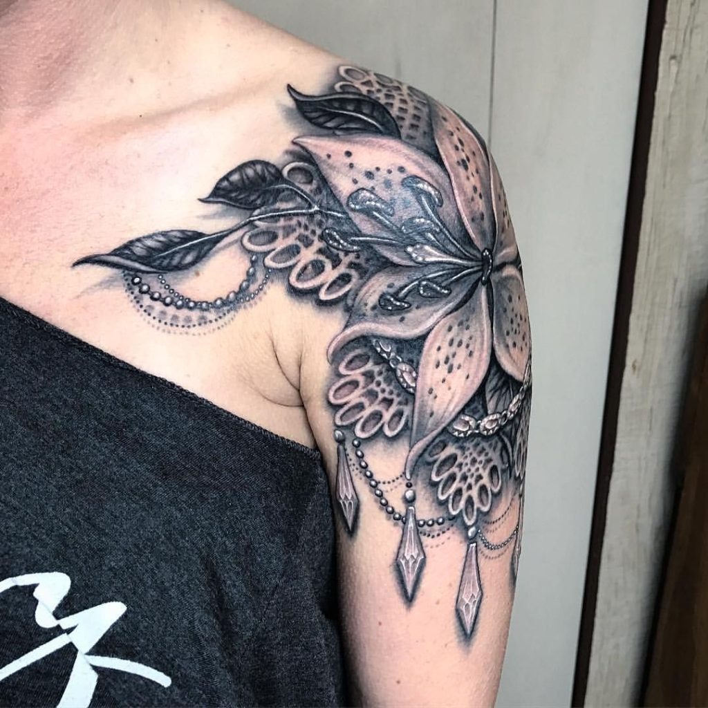 This stunning shoulder cap tattoo combines a large floral design with intricate beadwork, offering a bold women unique tattoo idea.