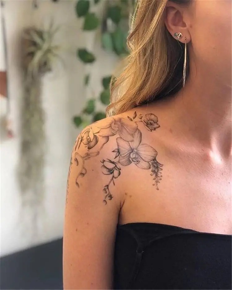 This feminine for women tattoo features a soft and elegant orchid design, flowing gracefully over the shoulder and collarbone.