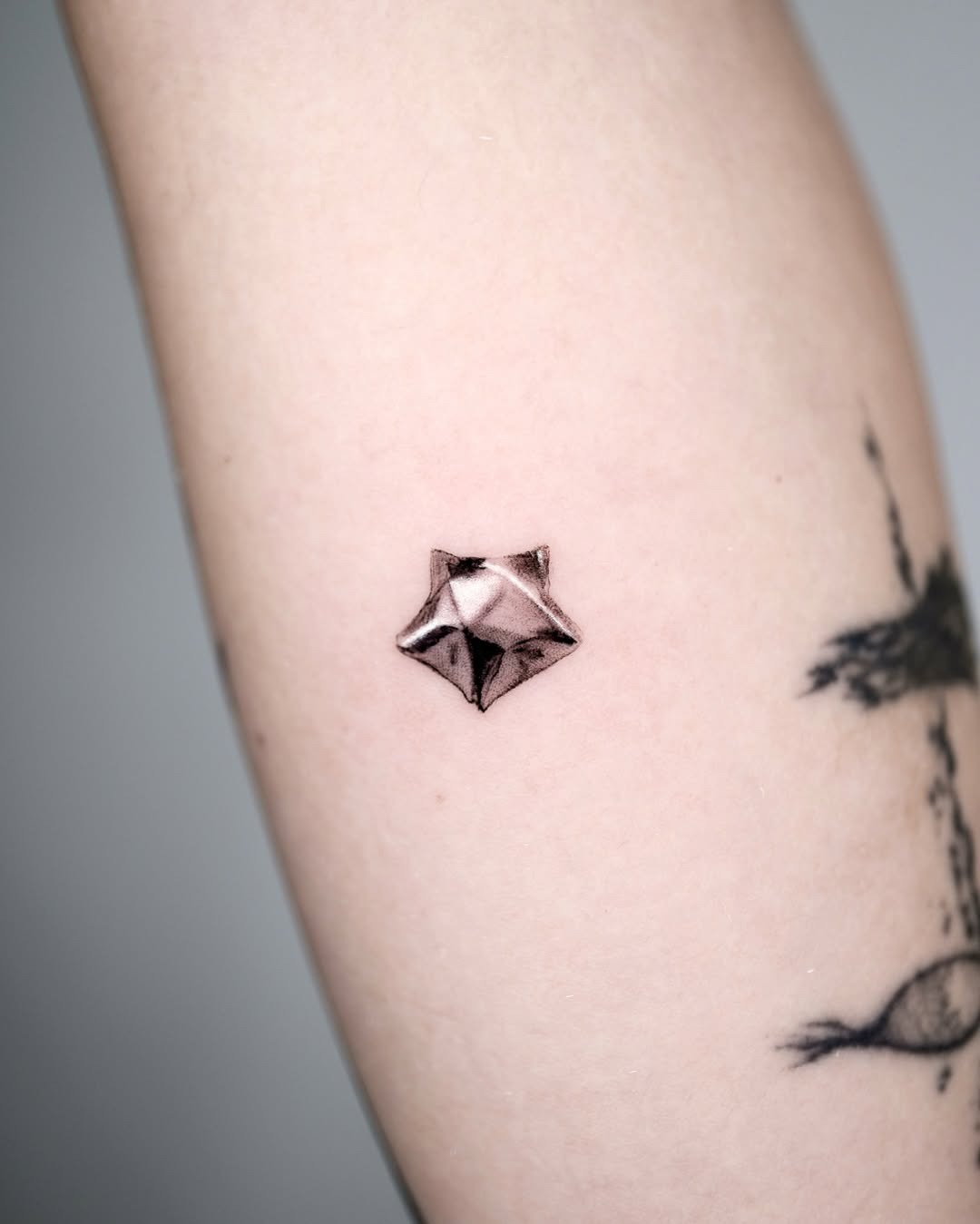 Stylish silver ink star tattoo on arm Tattoo Design