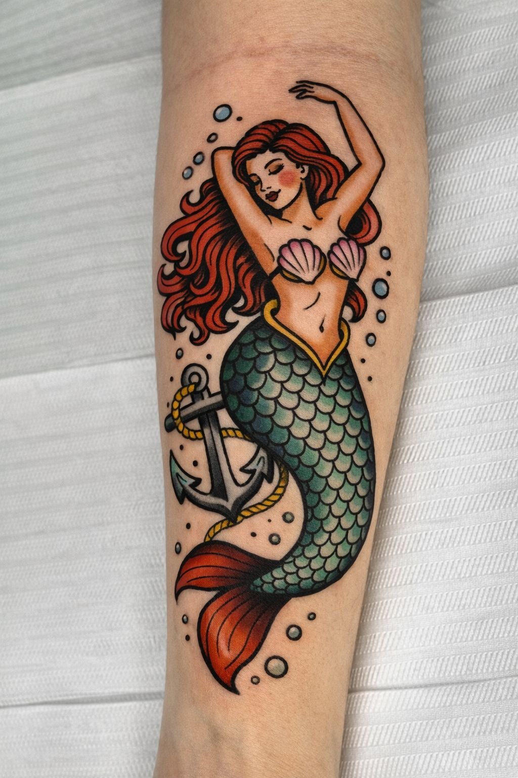 Classic American Traditional Red-Haired Mermaid, a tattoo design rendered in bold traditional for the arm.