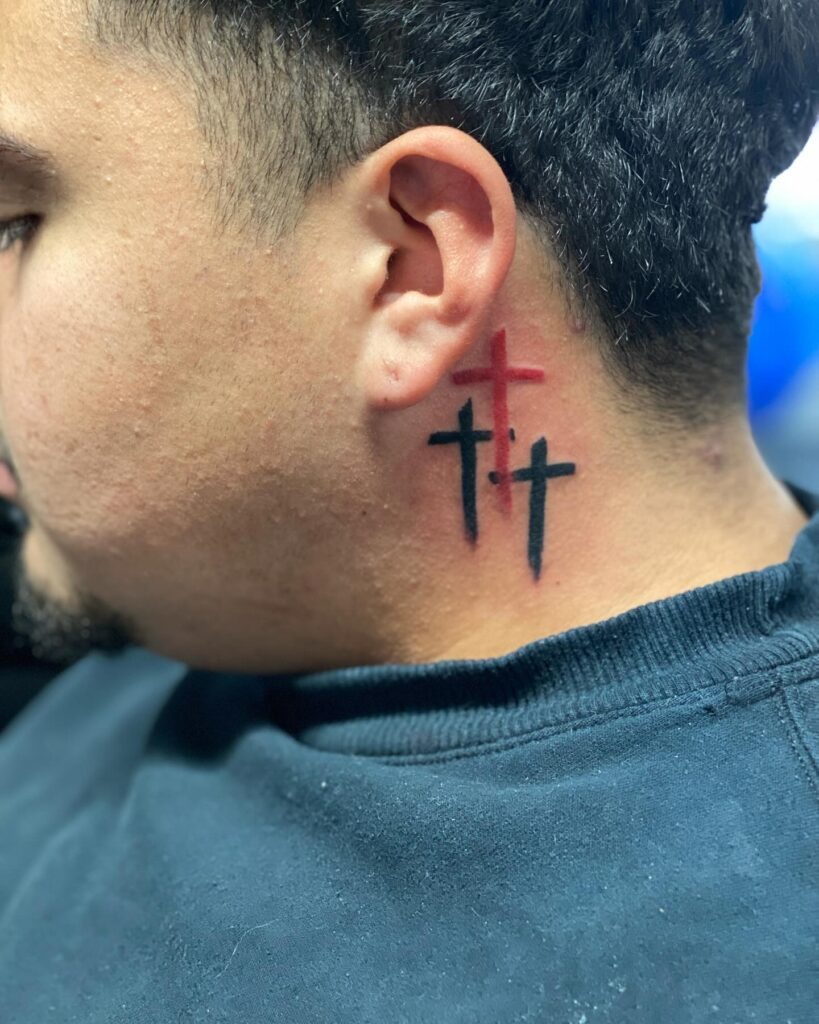 Three Crosses Behind Ear Tattoo with Red Accent Tattoo Design