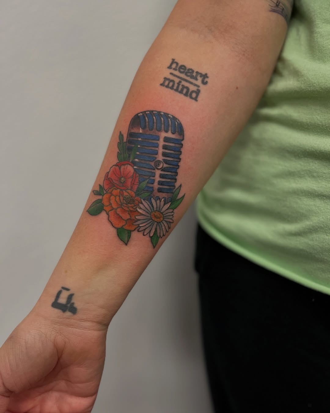This tattoo showcases a classic microphone adorned with flowers.