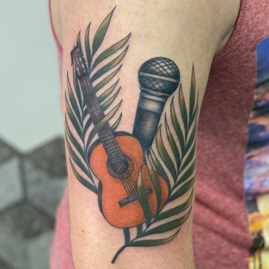 This tattoo features a microphone and guitar nestled among green leaves.Presenting a harmonious blend, it captures the essence of music and nature beautifully.