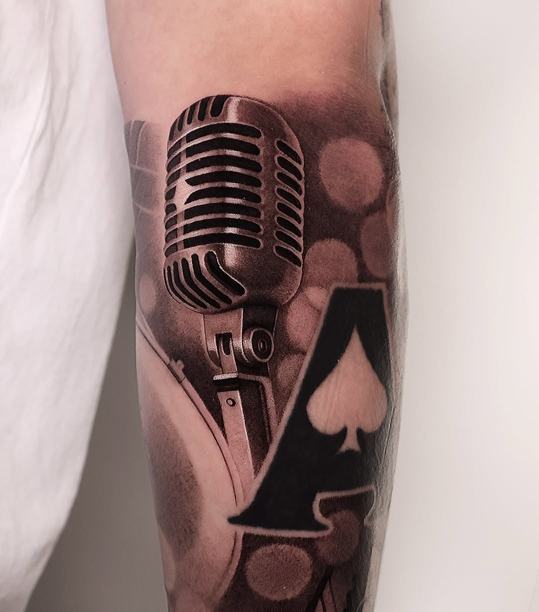 This striking microphone tattoo seamlessly blends with an ace card design.
