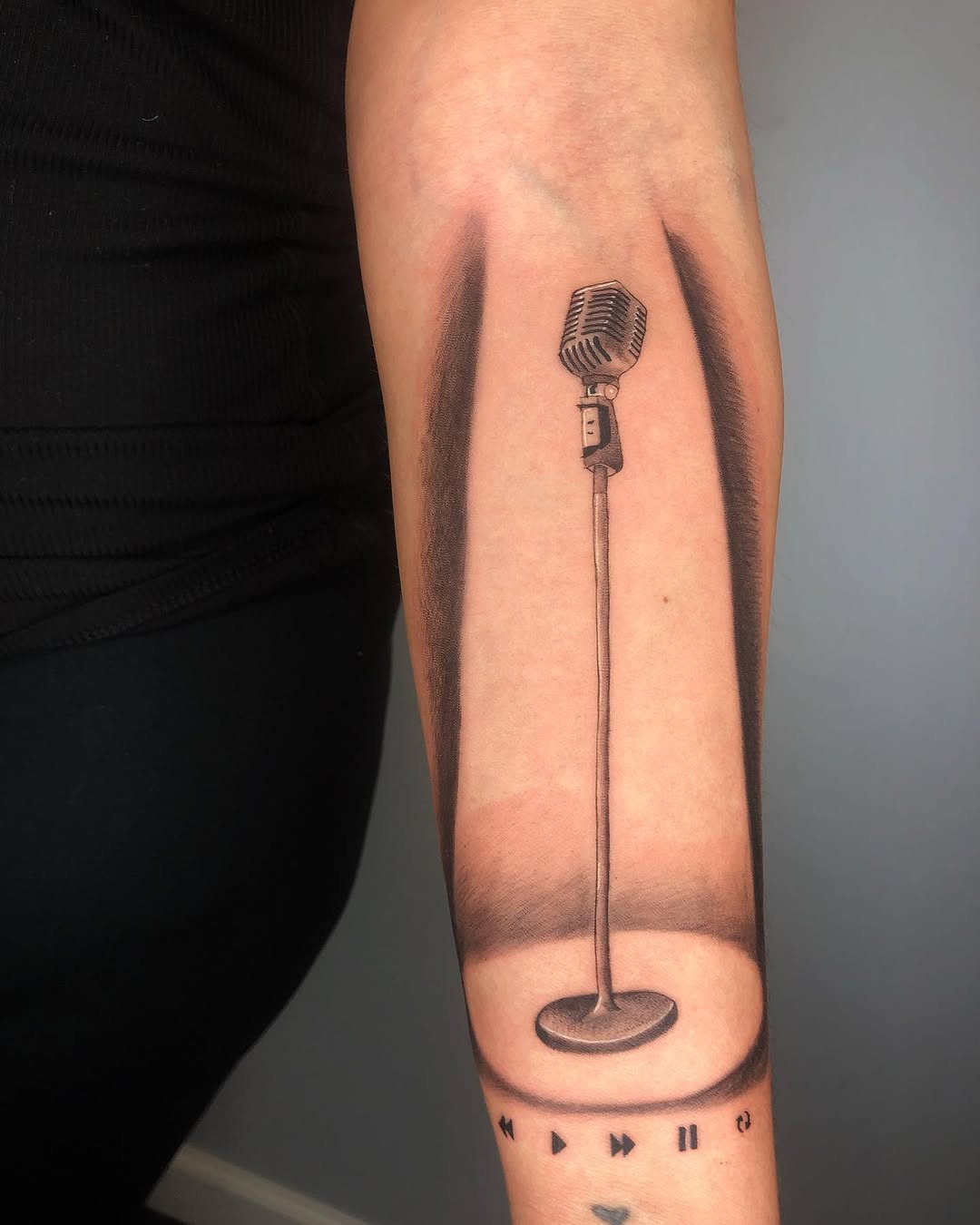 This tattoo features a classic microphone design with impressive shading, creating a three-dimensional effect.