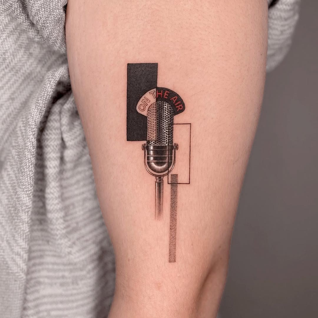 This tattoo features a vintage microphone surrounded by geometric shapes.