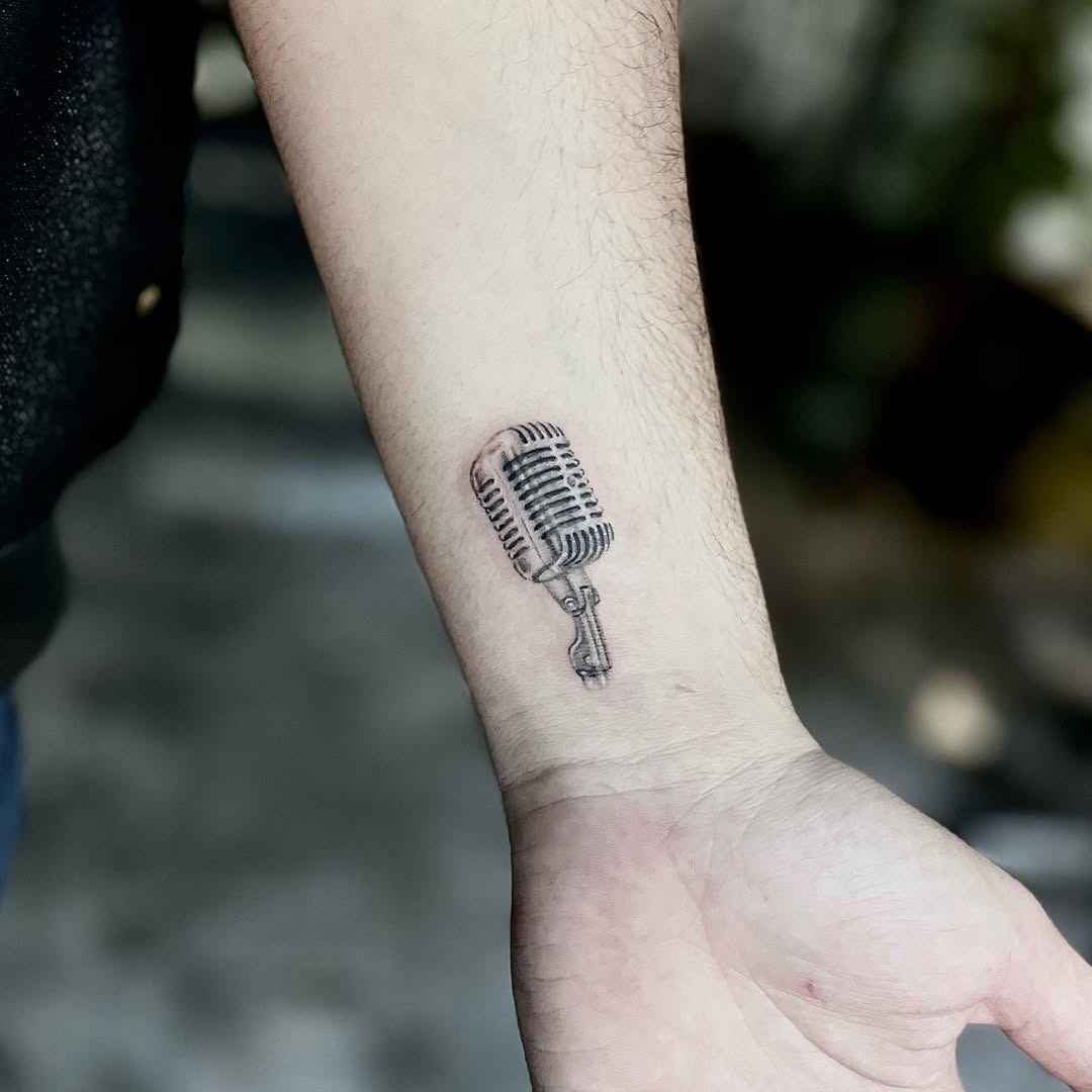 This tattoo showcases a vintage microphone beautifully nestled on the forearm.