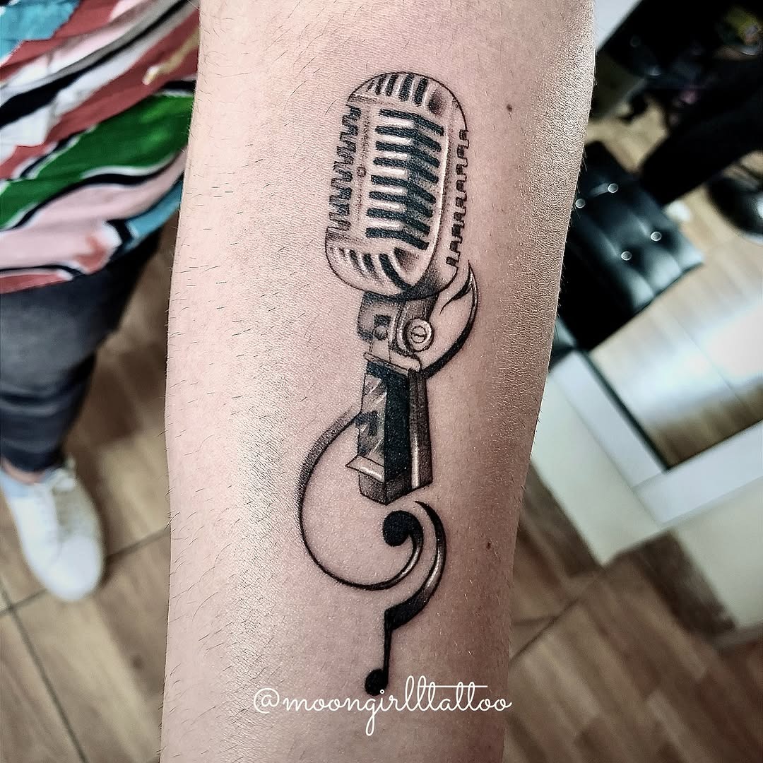 This tattoo features a classic microphone beautifully inked on the forearm.