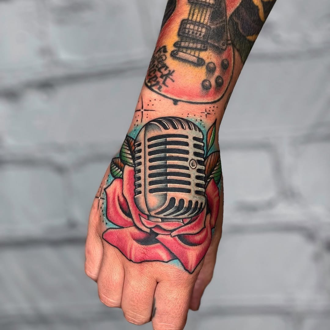 This striking tattoo features a vintage microphone nestled within a rose, creating a dynamic contrast.