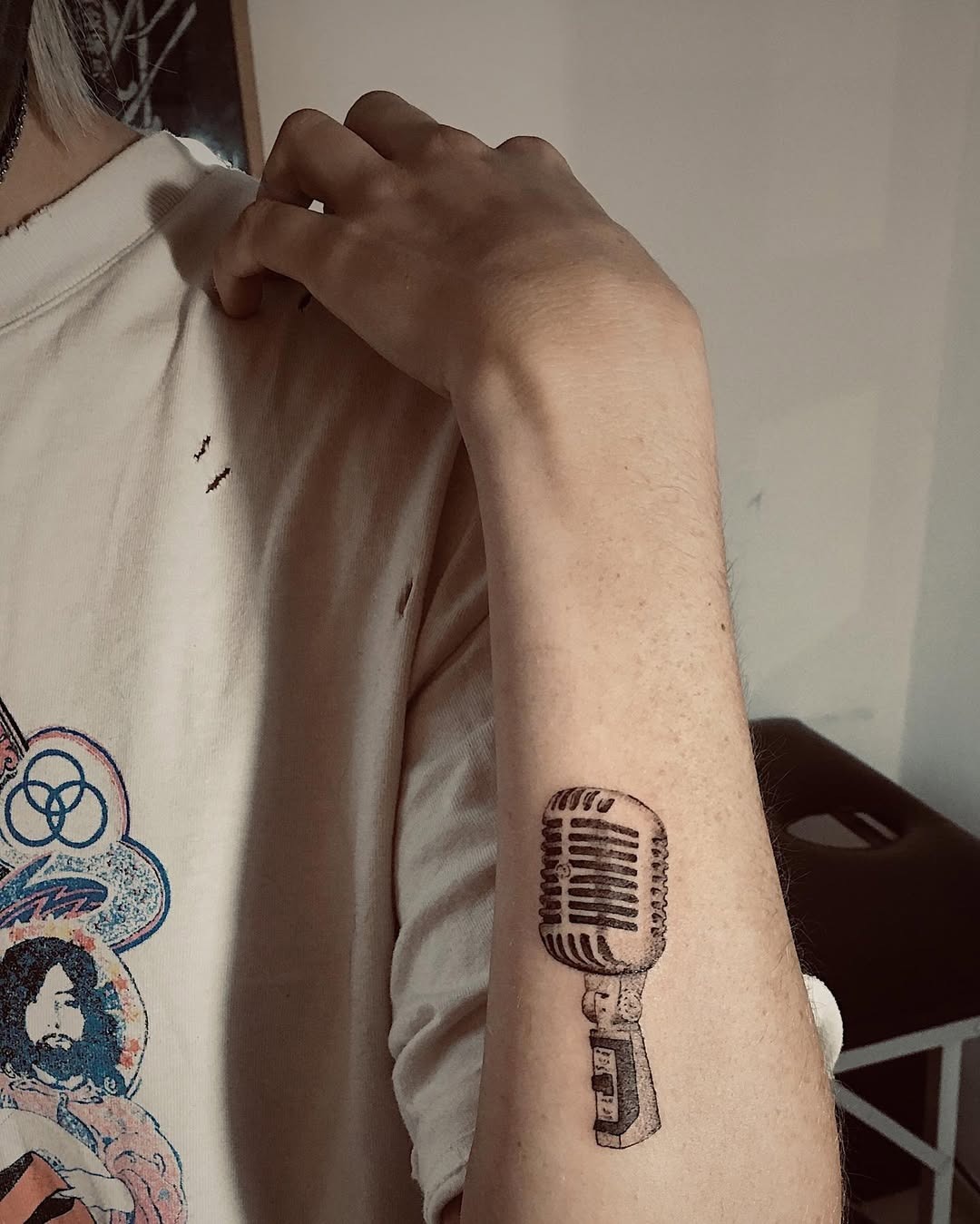 This tattoo features a classic vintage microphone elegantly inked on the inner arm.