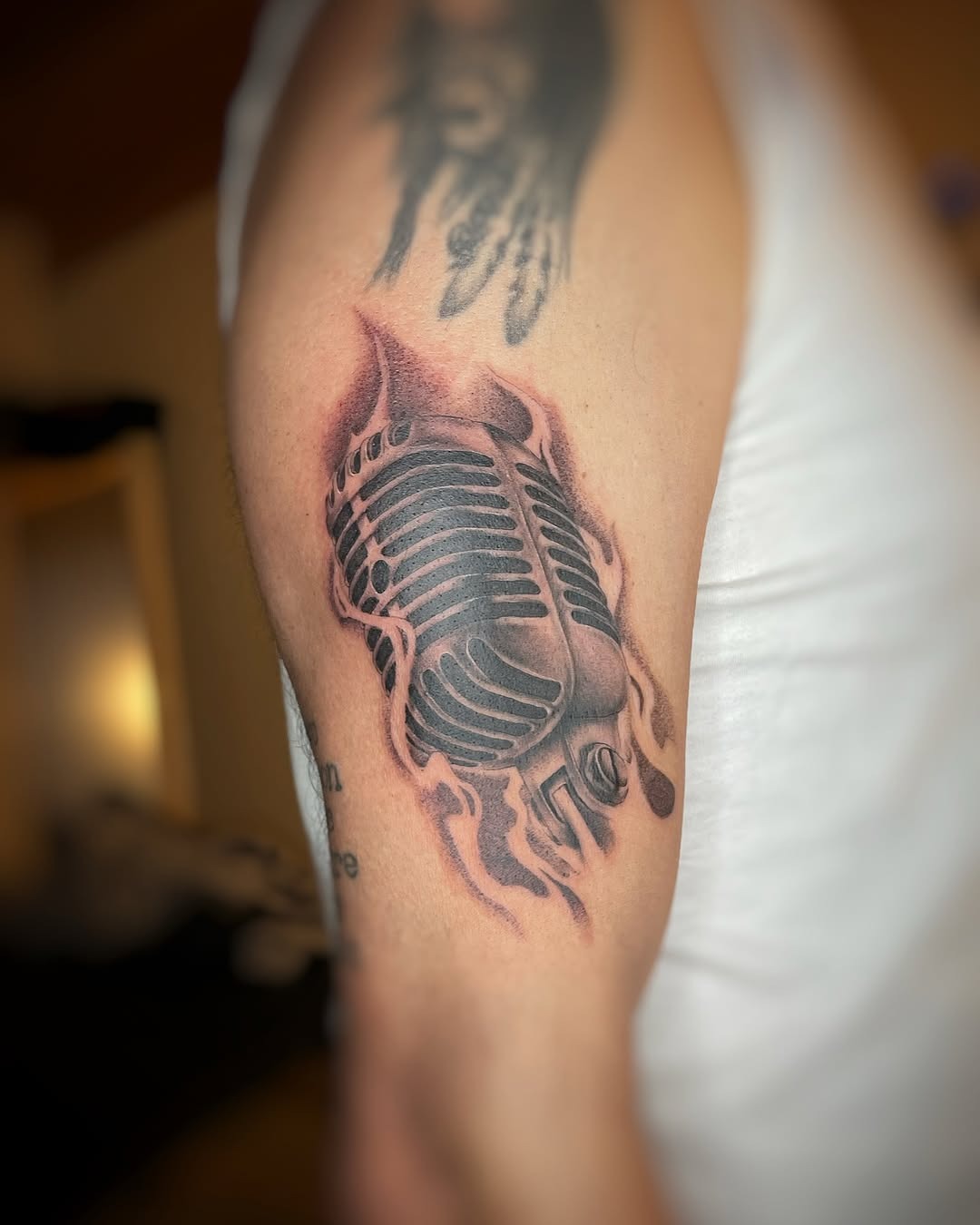 This tattoo features a retro microphone encased in flames, showing a unique blend of music and art.