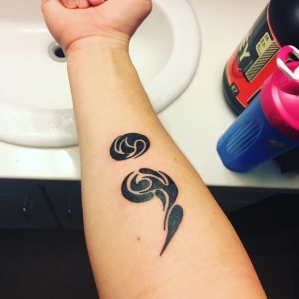 This intricate tribal-style semicolon tattoo features flowing geometric shapes that add a unique flair to the design.