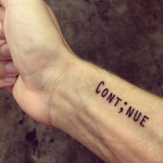 Merging typography with a semicolon, this tattoo spells out the word "continue," reinforcing the message of perseverance.