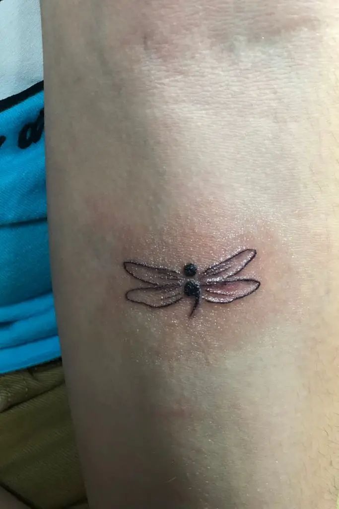 A dragonfly seamlessly integrates into the semicolon in this stylish design, symbolizing change, adaptability, and personal strength.