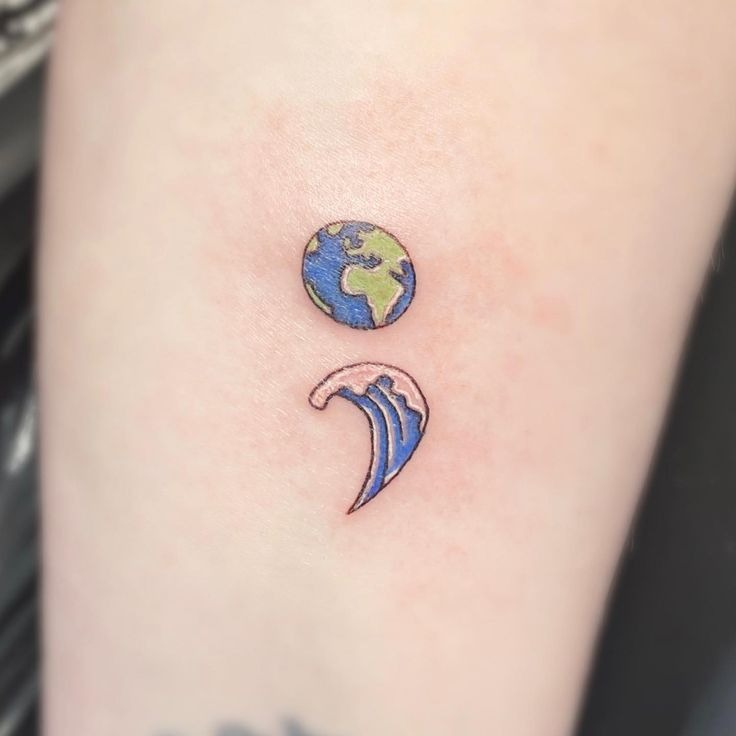This watercolor-style tattoo uniquely transforms the semicolon into the Earth and a wave, representing balance, nature, and fluidity.