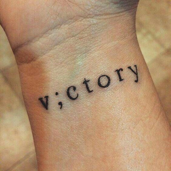 A bold play on words, this tattoo replaces the "I" in VICTORY with a semicolon, emphasizing the importance of perseverance.