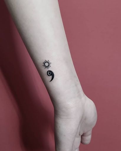 This delicate design combines a semicolon with a small sun, symbolizing new beginnings, warmth, and light overcoming darkness.