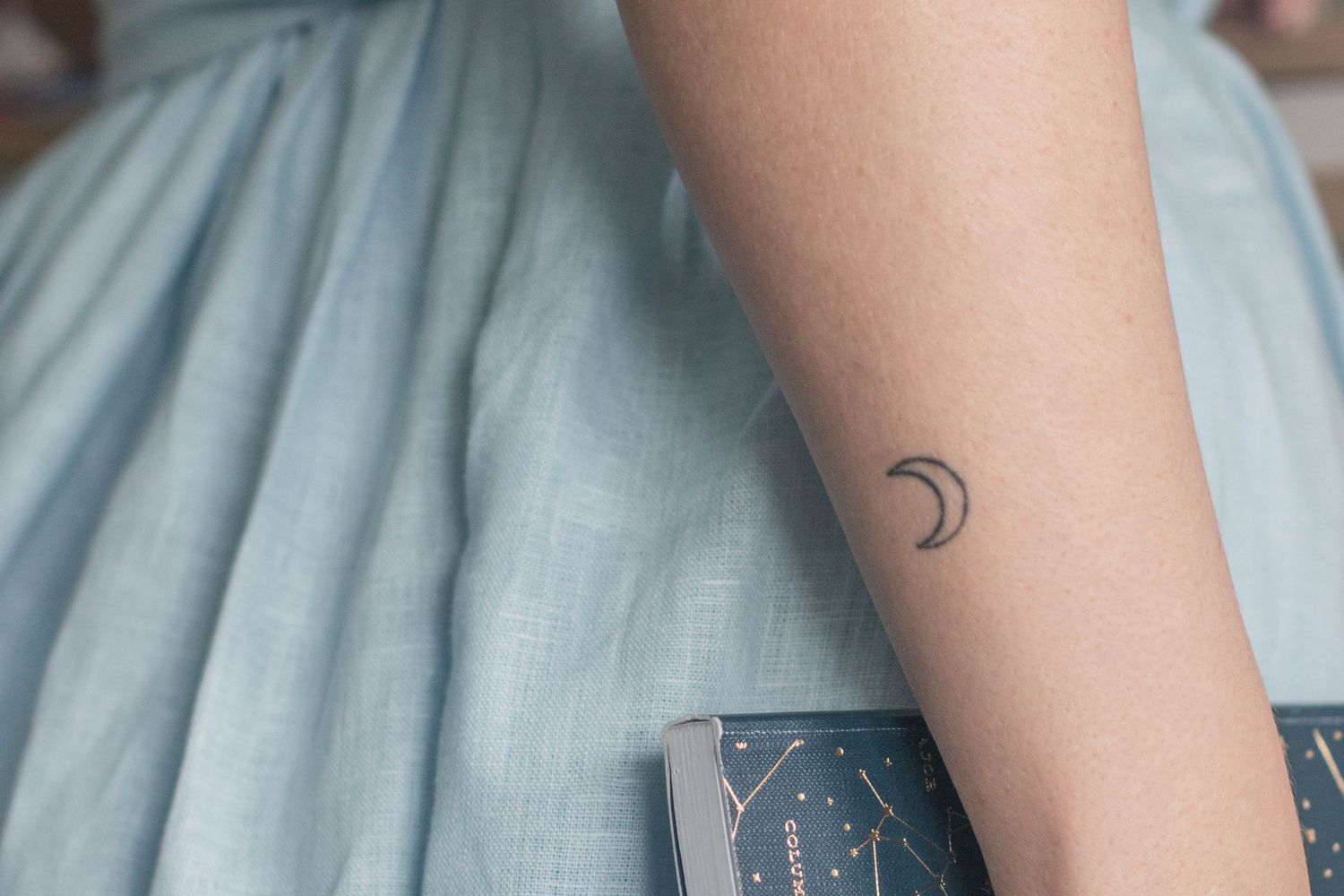 Small crescent moon tattoo on a forearm