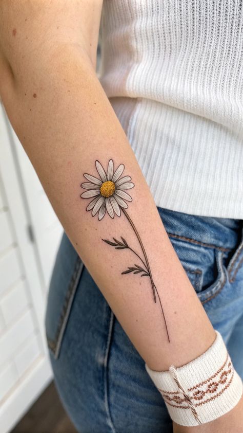 Small daisy flower tattoo on a forearm