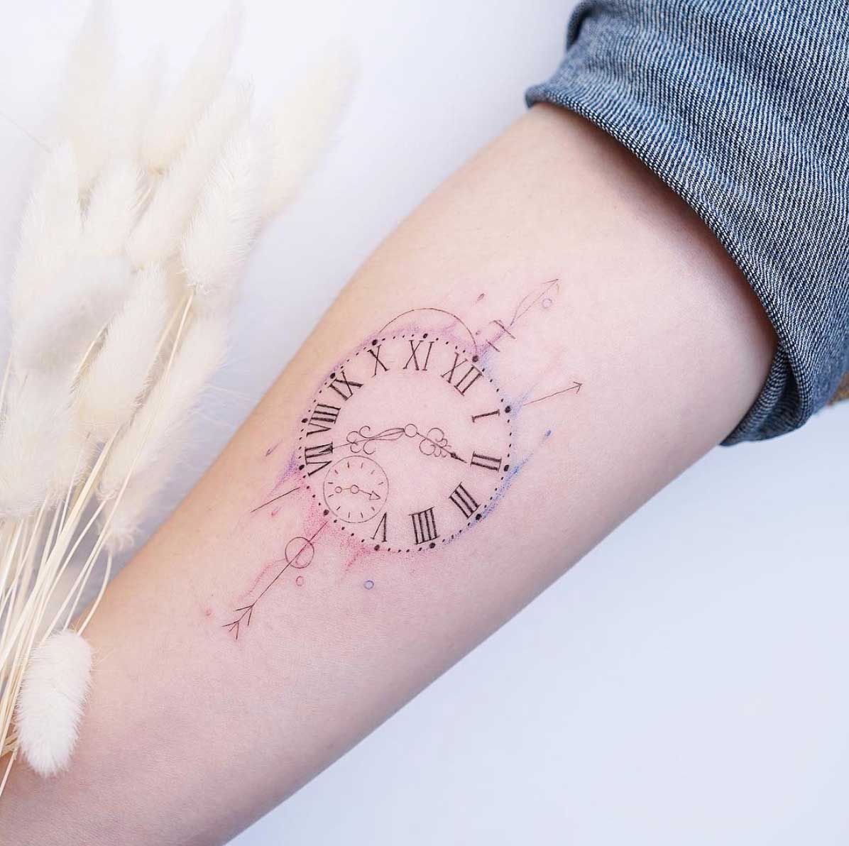 Delicate clock face tattoo with roman numerals on a forearm
