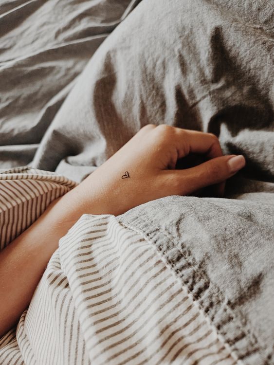 Tiny heart outline tattoo on a hand