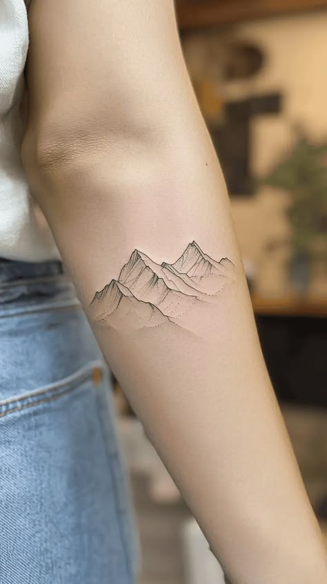Minimalist mountain range tattoo on a forearm